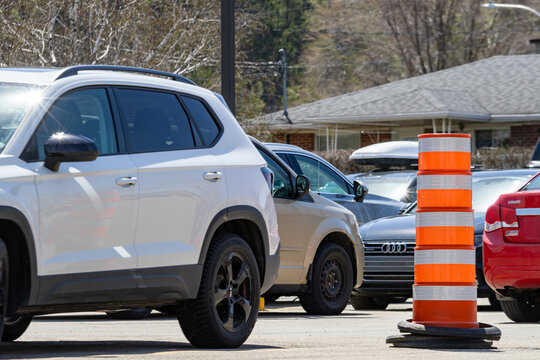La Tuque, Quebec, 16 May 2026 : Various cars, including a white SUV and a red Chevrolet Cruze, are parked near an orange traffic barrel.