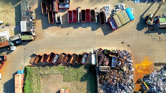 Aerial Top-Down Drone Footage of a Scrapyard with Heavy Machinery Sorting Piles of Scrap Metal for Recycling