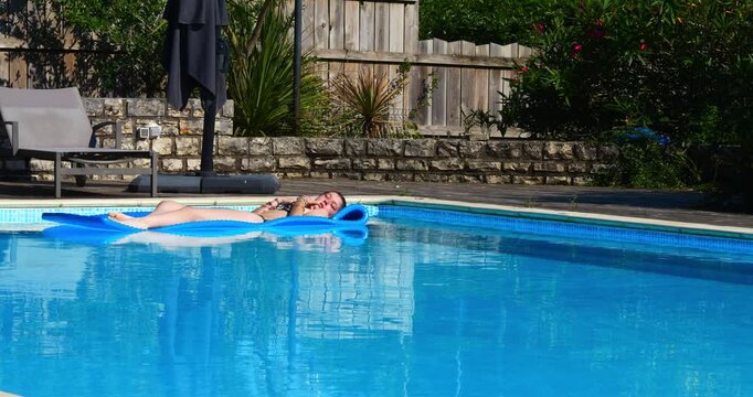 Beautiful young girl enjoying lounging in the swimming pool during heatwave