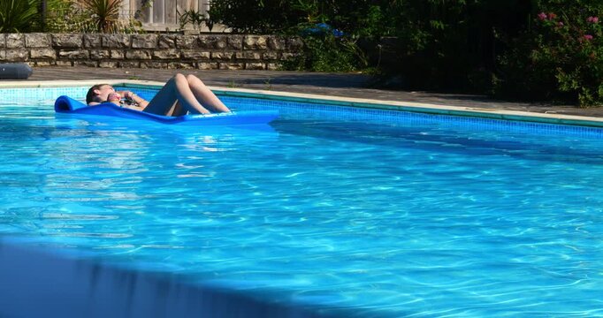 Beautiful young girl enjoying lounging in the swimming pool during heatwave
