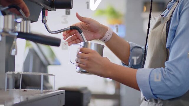 Barista placing pitcher under steam wand, aligning for steaming while white alphanumeric overlaying