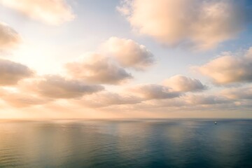 Fototapeta premium Aerial view of fluffy clouds above a calm ocean during golden hour, soft cinematic lighting, peaceful dreamy atmosphere, minimalist wide composition for social media header 