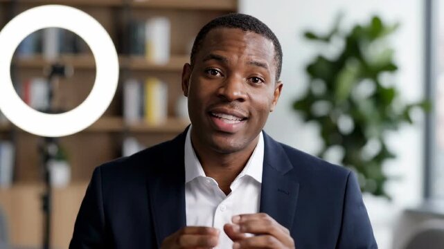 Businessman video call ring light home office online meeting professional remote work webcam speaking communication modern workspace bookshelf background confident presenter entrepreneur portrait