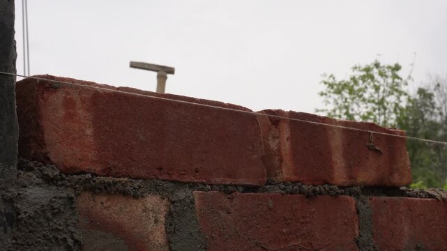 Worker Building Brick Wall with Red Bricks and Mortar