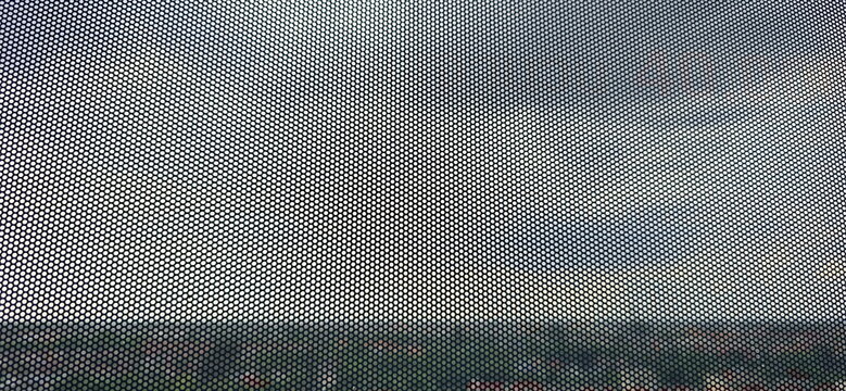 An enlarged image of a see-through sticker, which has small perforations throughout the sheet. One Way Vision, thick PVC material with small perforations. Similar to perforated metal plate.
