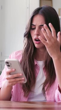 Young stressed woman reacting with frustration and despair while reading bad news, a text message, or an email on her smartphone, displaying anxiety and disappointment at home