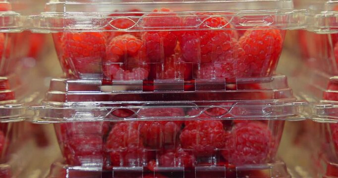 Bright red raspberries packed in clear plastic containers, stacked in a store. Fresh produce, healthy eating, and grocery shopping concept. Vibrant, natural light.