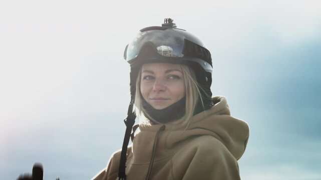 Lovely girl snowboarder rider is dancing. Happy skiing. Wearing a hoodie and a protective helmet. Travel to winter resort, adventure.