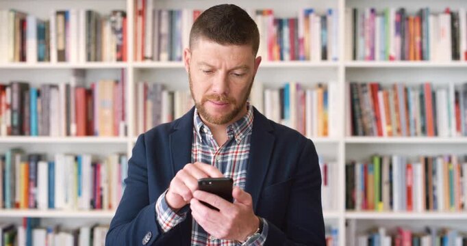 Phone, business and man in library for typing, communication or research for book update. Mature author, news and person scroll, reading or information for about us and literature review or knowledge