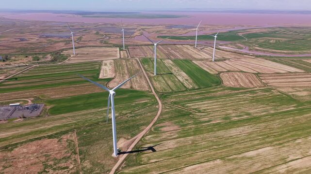 An aerial view of a field filled with windmills. The windmills stand close to a river and the ocean in Nova Scotia. This area highlights renewable energy technology