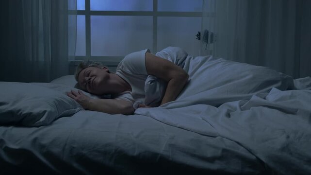 Woman sleeps sweetly lying in bed in bedroom at night.
