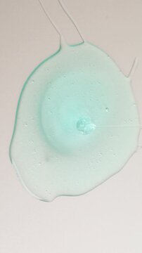 Blue cream liquid gel serum flowing down on silver texture, makeup and cosmetics background, skincare or hair product
