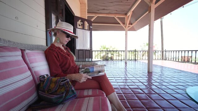Mature woman relaxes reading a magazine and looks around in Santa Rosalia, Baja California Mexico while enjoying the warm weather and beautiful views