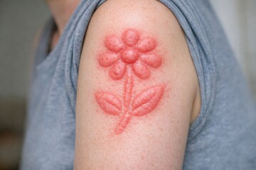 Fototapeta premium A close-up shot of a woman with a colorful flower tattoo on her arm, suitable for use in designs about individuality, self-expression, and personal style