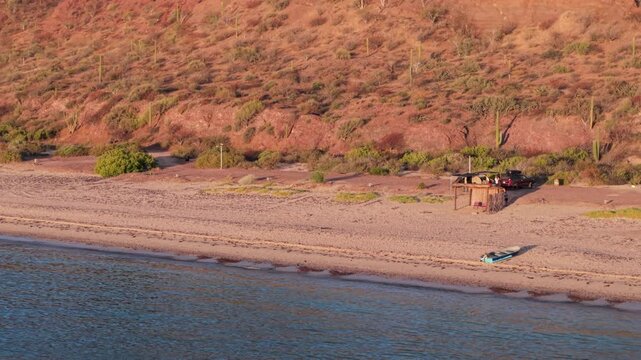 A teardrop camper trailer sits on the beach in Santa Ines Mulege Baja California Sur. A new day begins over the Sea of Cortez.