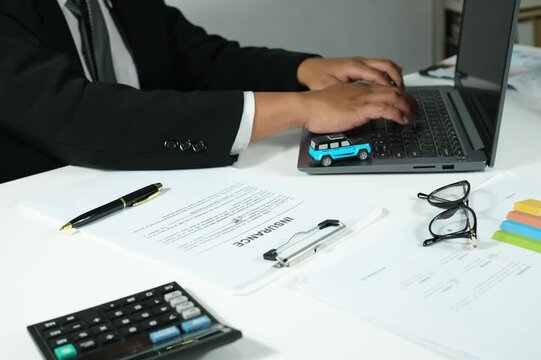 A businessman inputs car insurance data into a laptop. Updating customer data, insurance claims, or payments digitally. The concept of integrating business and technology.
