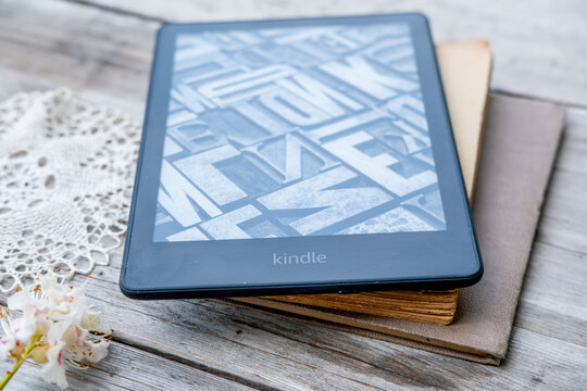 Modern ebook Kindle reader on stack old paper books on wooden table, electronic book, digital reading device and vintage literature contrast, technology vs tradition, Back to school and education