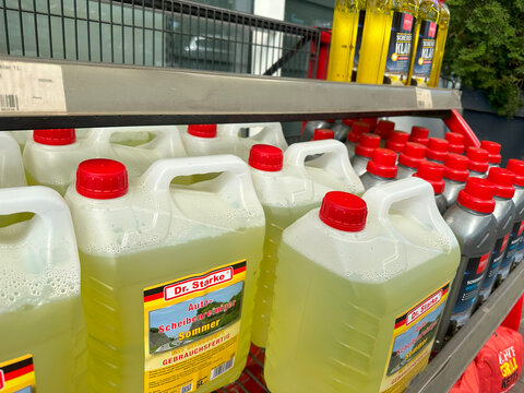 Shelves stocked with automotive fluids, including Liqui Moly antifreeze and Dr. Starke summer windshield washer fluid, in German auto parts store, car maintenance essentials, care products, Frankfurt