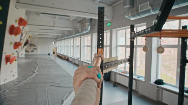 Athletic young woman performing pull-ups on horizontal bar in climbing gym. Footage serves fitness training programs and sports lifestyle commercial campaigns, close up view