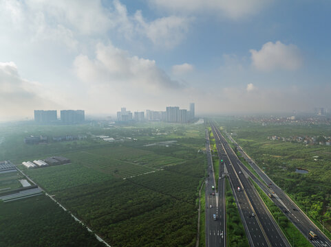 Aerial view of Hanoi Hai Phong Expressway 5B cutting through green suburban landscapes under hazy morning skies in northern Vietnam.