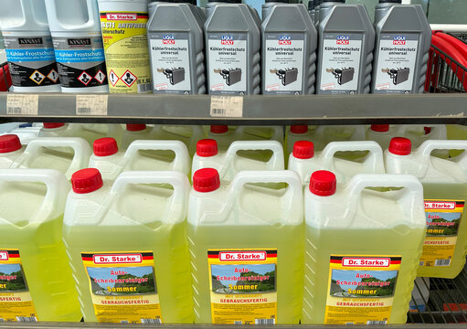 Shelves stocked with automotive fluids, including Liqui Moly antifreeze and Dr. Starke summer windshield washer fluid, in German auto parts store, car maintenance essentials, care products, Frankfurt