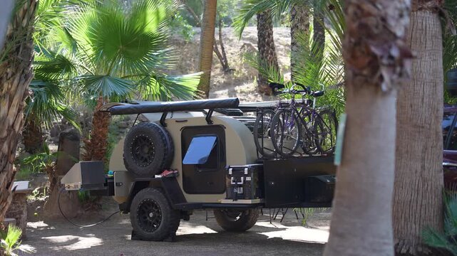 Discover a teardrop camper trailer parked in a desert oasis with palm trees in San Ignacio, Baja California Sur as the morning light shines.