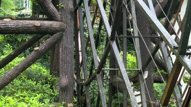 Old wooden water wheel rotating in small forest stream. Rustic antique mechanism for energy production and grinding. Historical water mill construction lush green nature landscape. Watermill closeup.