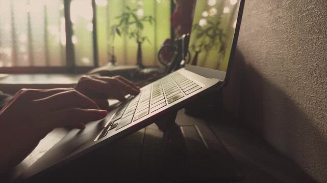 Hands Typing on Laptop Computer with Green Plants Background, Work from Home