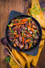 Classic traditional French coq au vin in red wine with mushrooms and caramelised baby carrots...