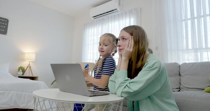 Slow motion caucasian single mother sits with preschool daughter behind laptop, guiding online learning, calm conversation, screen time supervision, nurturing care, cozy home education routine.