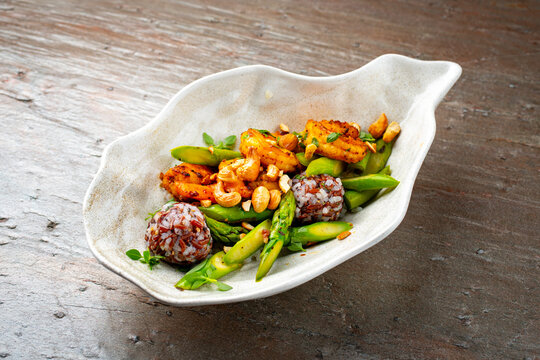 Green asparagus with spicy prawns and natural mixed wild brown and white rice with cashew nute in a shell design bowl