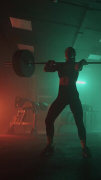 Athletes performing functional training with heavy barbell lifts in a dimly lit gym environment, focusing on strength, power, and endurance during weightlifting exercises