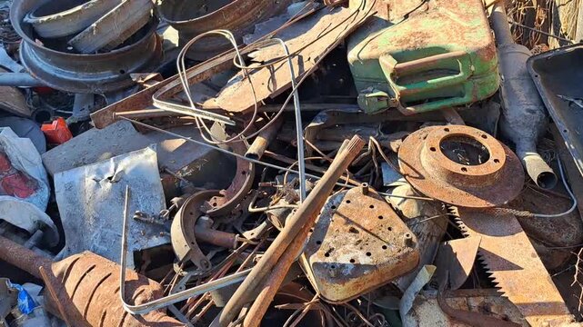 Pile of rusty scrap metal and old car parts in outdoor junkyard