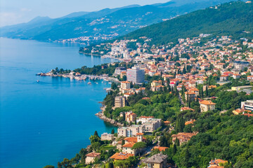 Naklejka premium Scenic aerial panorama of Opatija Riviera and Volosko coastline in Croatia with Adriatic Sea, lush green hills and elegant seaside architecture under clear blue sky