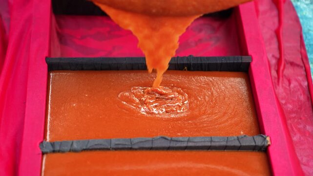 View of thick traditional date palm jaggery being poured into rectangular molds during the production process in Natore, Rajshahi Division, Bangladesh.