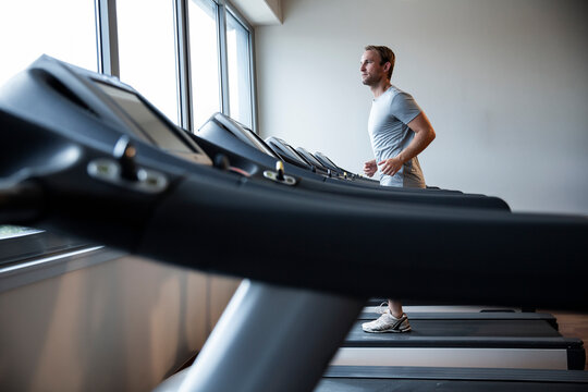 Man Running on a Treadmill in a Modern Fitness Studio