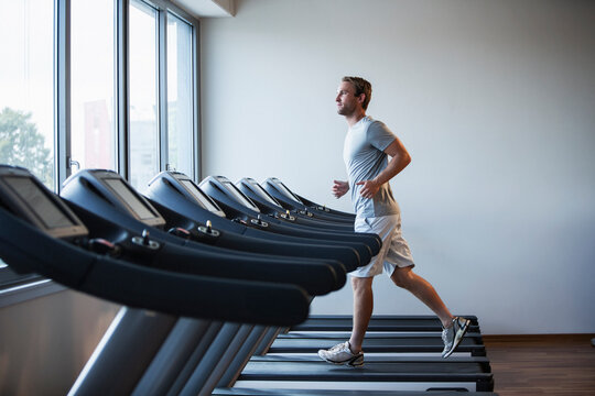 Man Running on a Treadmill in a Modern Fitness Studio