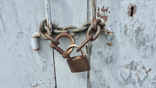Rusty lock on weathered blue door: urban decay and vintage charm.