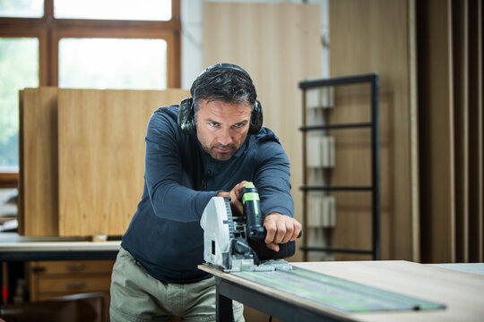 Carpenter Measuring, Cutting, and Assembling Wood in a Workshop