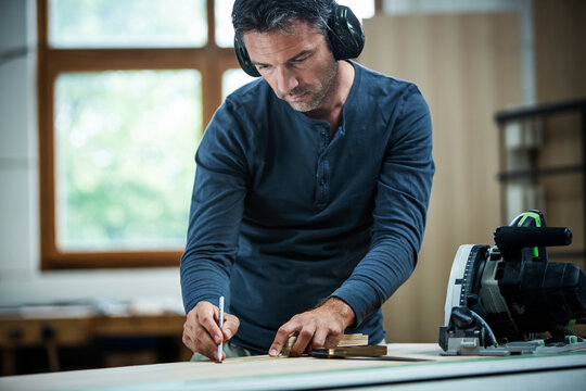Carpenter Measuring, Cutting, and Assembling Wood in a Workshop