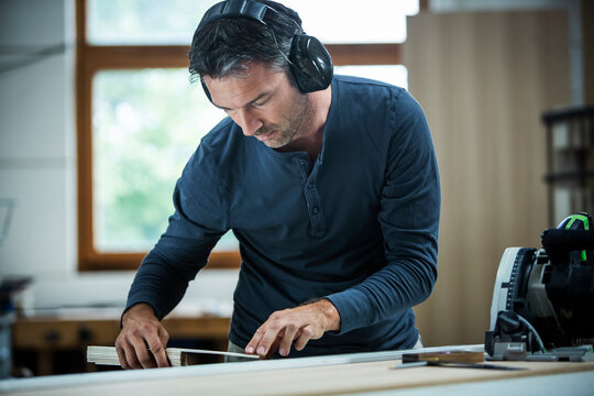 Carpenter Measuring, Cutting, and Assembling Wood in a Workshop