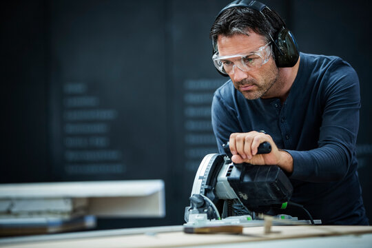 Carpenter Measuring, Cutting, and Assembling Wood in a Workshop