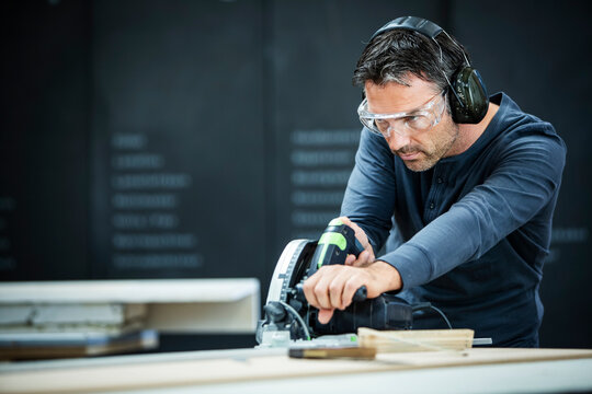 Carpenter Measuring, Cutting, and Assembling Wood in a Workshop