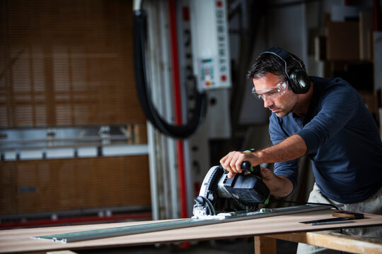 Man cutting wood with track saw in a wood working shop