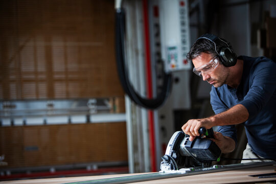 Man cutting wood with track saw in a wood working shop