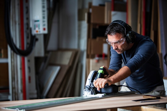 Man cutting wood with track saw in a wood working shop