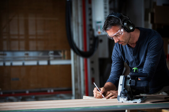 Man cutting wood with track saw in a wood working shop