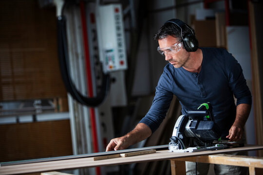 Man cutting wood with track saw in a wood working shop