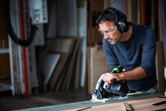 Man cutting wood with track saw in a wood working shop