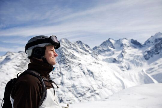 Skier standing on a mountain with helmet looking into the distance of mountains.